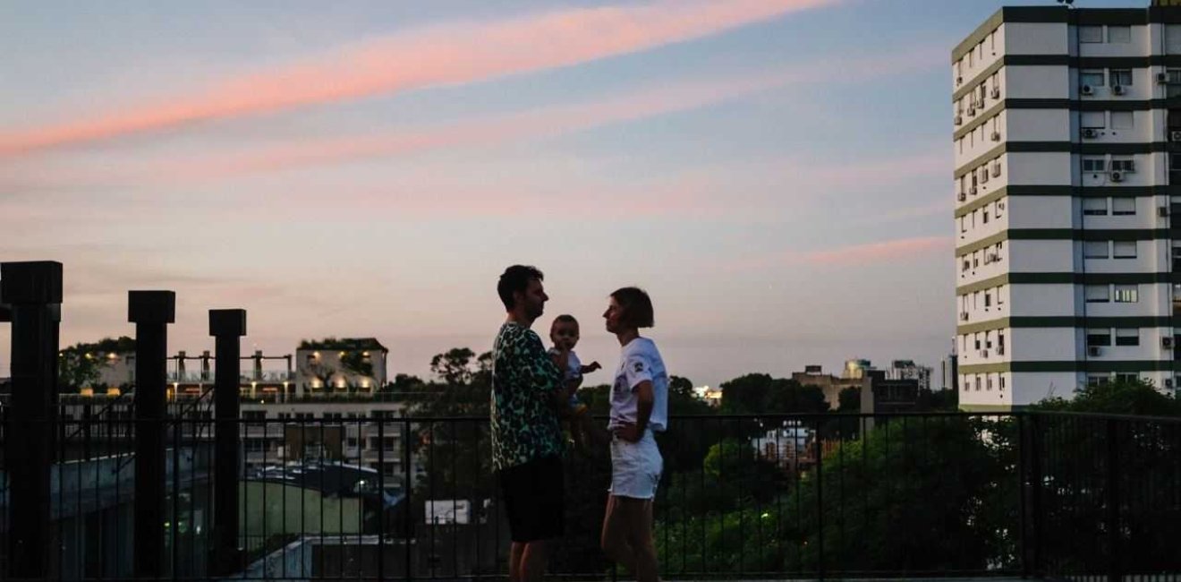 Husband, wife, and baby on balcony overlooking city 