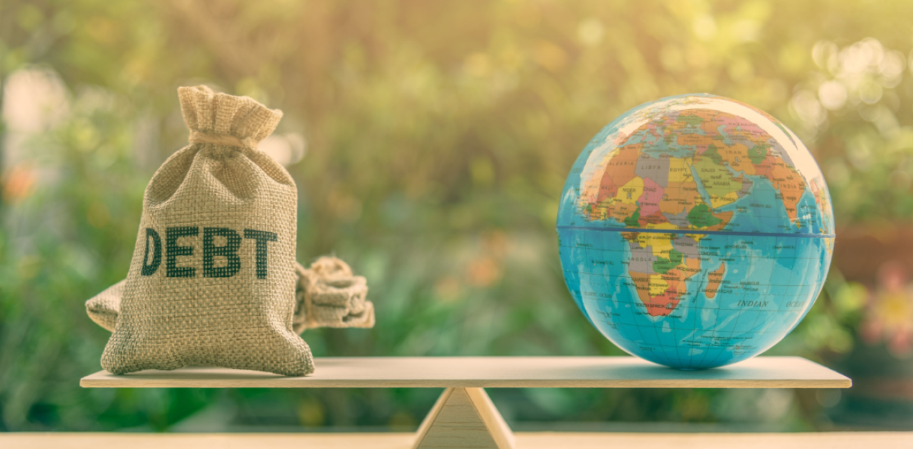 A globe and bag marked 'debt' balance on a scale