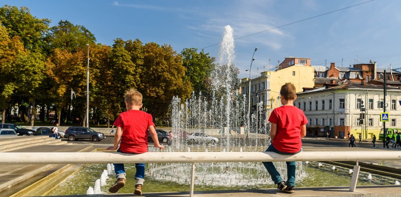  boys sit and look at the fountain in the center of Kharkiv, Ukraine