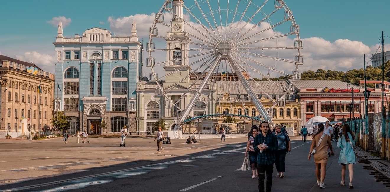 Podil, Kyiv, Ukraine - June 16, 2021 - street shot of people on the main square of the Podil neighborhood with ferris wheel and traditional architecture