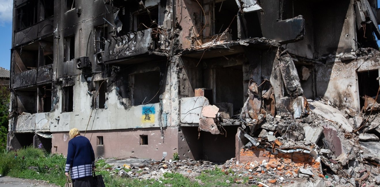 old woman walks past apartment building destroyed by the Russian army as a result of Russia's invasion of Ukraine in Borodianka, Ukraine