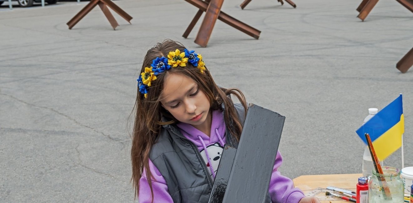 Young person painting wearing flower crown with Ukrainian National Colors