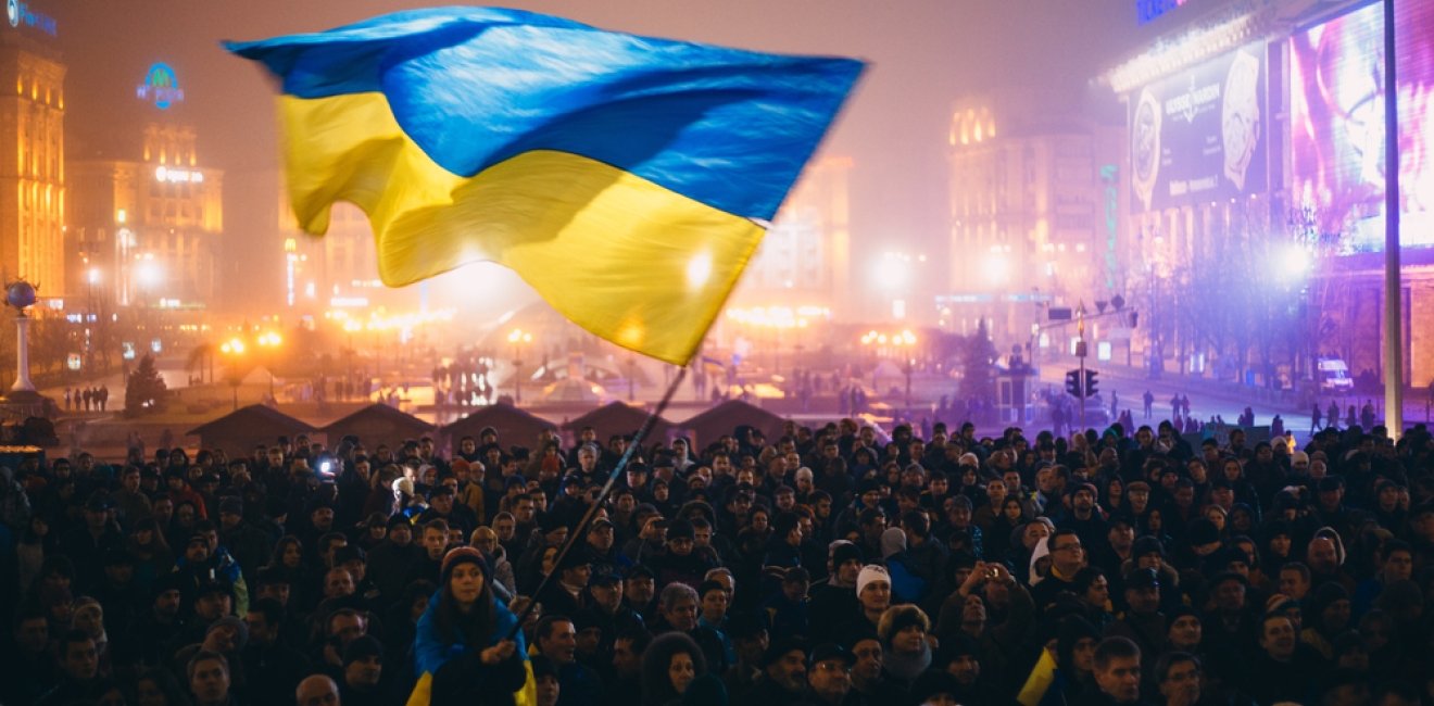 A Ukrainian flag is waved over a busy square. 