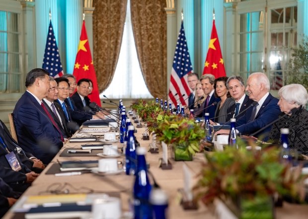 Delegations sit on opposite sides of a long conference table, President Xi on the left side and President Biden on the right.