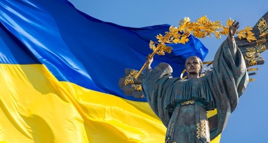 Monument of Independence of Ukraine in front of the Ukrainian flag. The monument is located in the center of Kyiv on Independence Square.