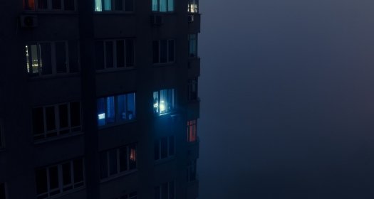 Person shining flashlight from a dark apartment building 