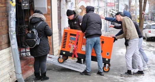 Group of men bringing an orange generator through a doorway