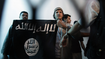 n this April 23, 2013 file photo, a suspected Yemeni al-Qaida militant, center, holds a banner as he stands behind bars during a court hearing in state security court in Sanaa, Yemen