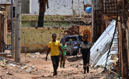 Young people walk along a street marked by destruction. A bloody power struggle has been raging in Sudan for more than 16 months, triggering a refugee crisis. Mudathir Hameed/picture-alliance/dpa/AP Images.