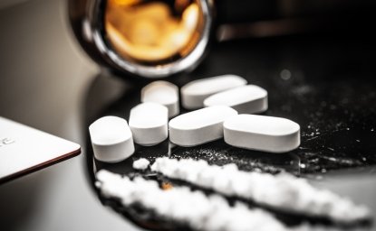 A detailed view of fentanyl pills and white powder on a reflective surface, illustrating the opioid crisis and prescription drug misuse. Subtle reflections and contemporary elements enhance the scene.