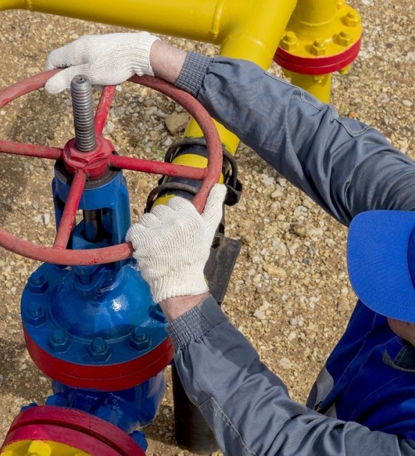 Image of a worker opening, closing the shut-off valves at the gas pumping station. Part of the photo is blurry.