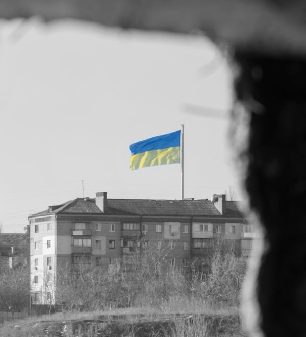 View through the window of the ruined house on the flag of Ukraine in the blue sky. Russia's aggression against Ukraine. The concept of peace after the war.f