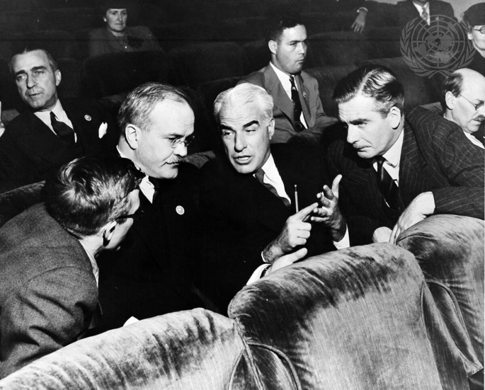 Three men in discussion in UN seats