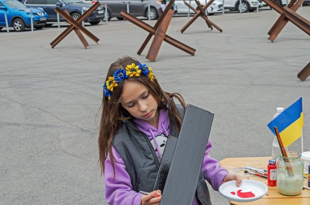 Young person painting wearing flower crown with Ukrainian National Colors