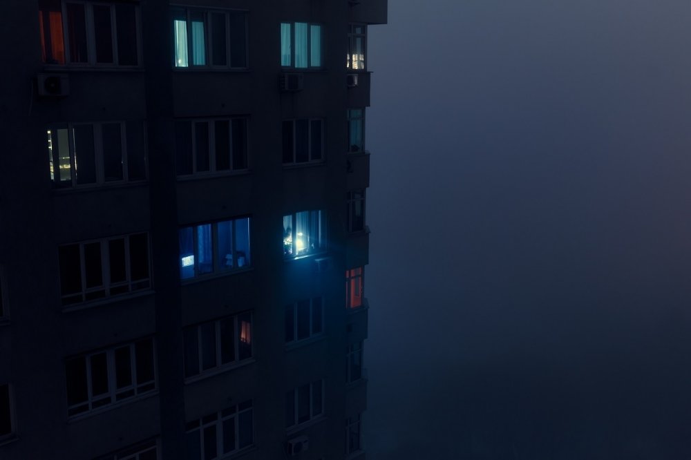 Person shining flashlight from a dark apartment building 