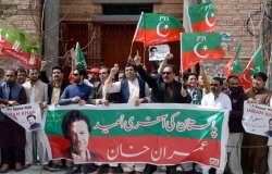 A group of Tehreek-e-Insaf supporters with a large banners and signs.