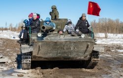 Visitors with children ride in the Soviet amphibious tank of PT-76 on a sunny March day.